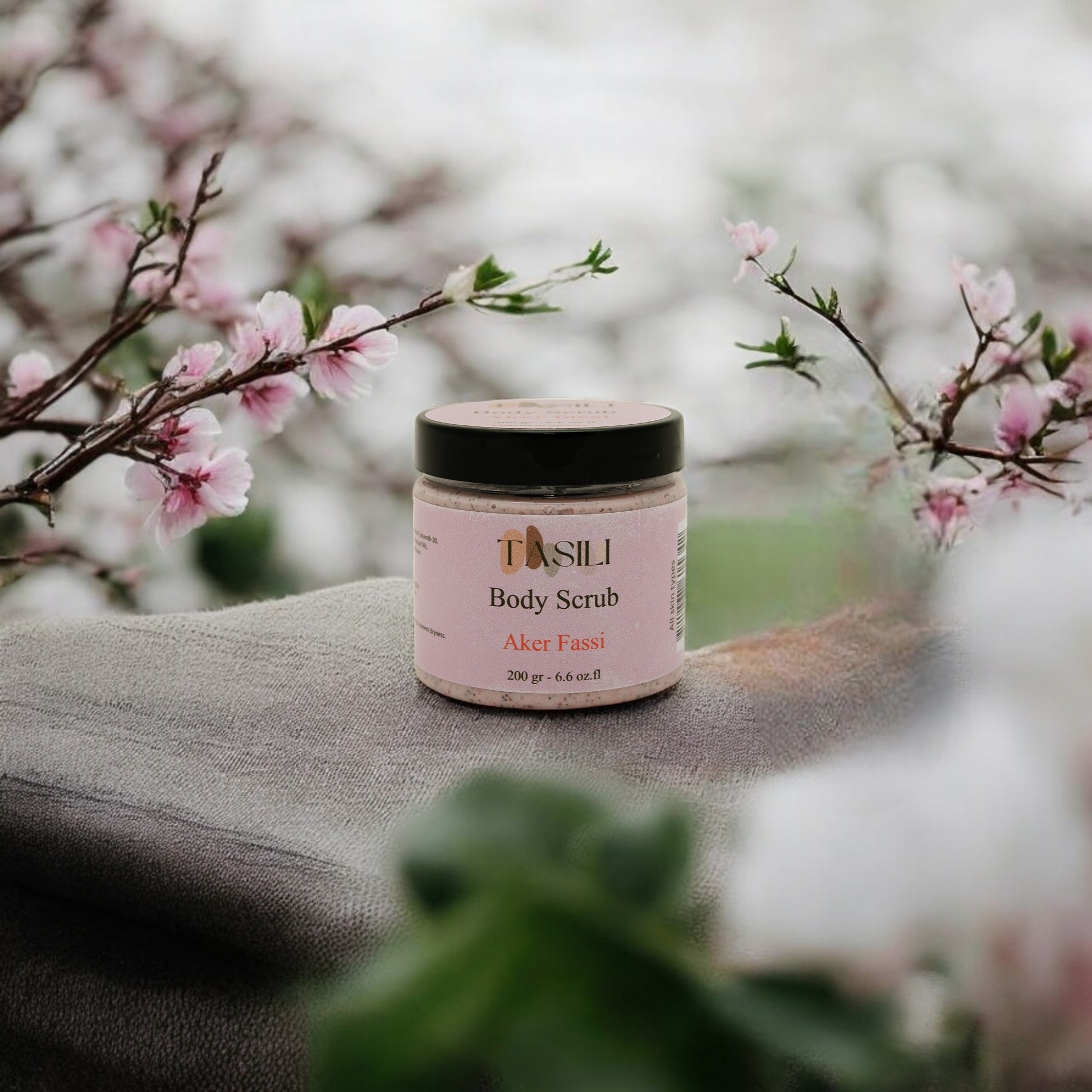 Akker Fassi Body Scrub on a towl surrounded by pink flowers